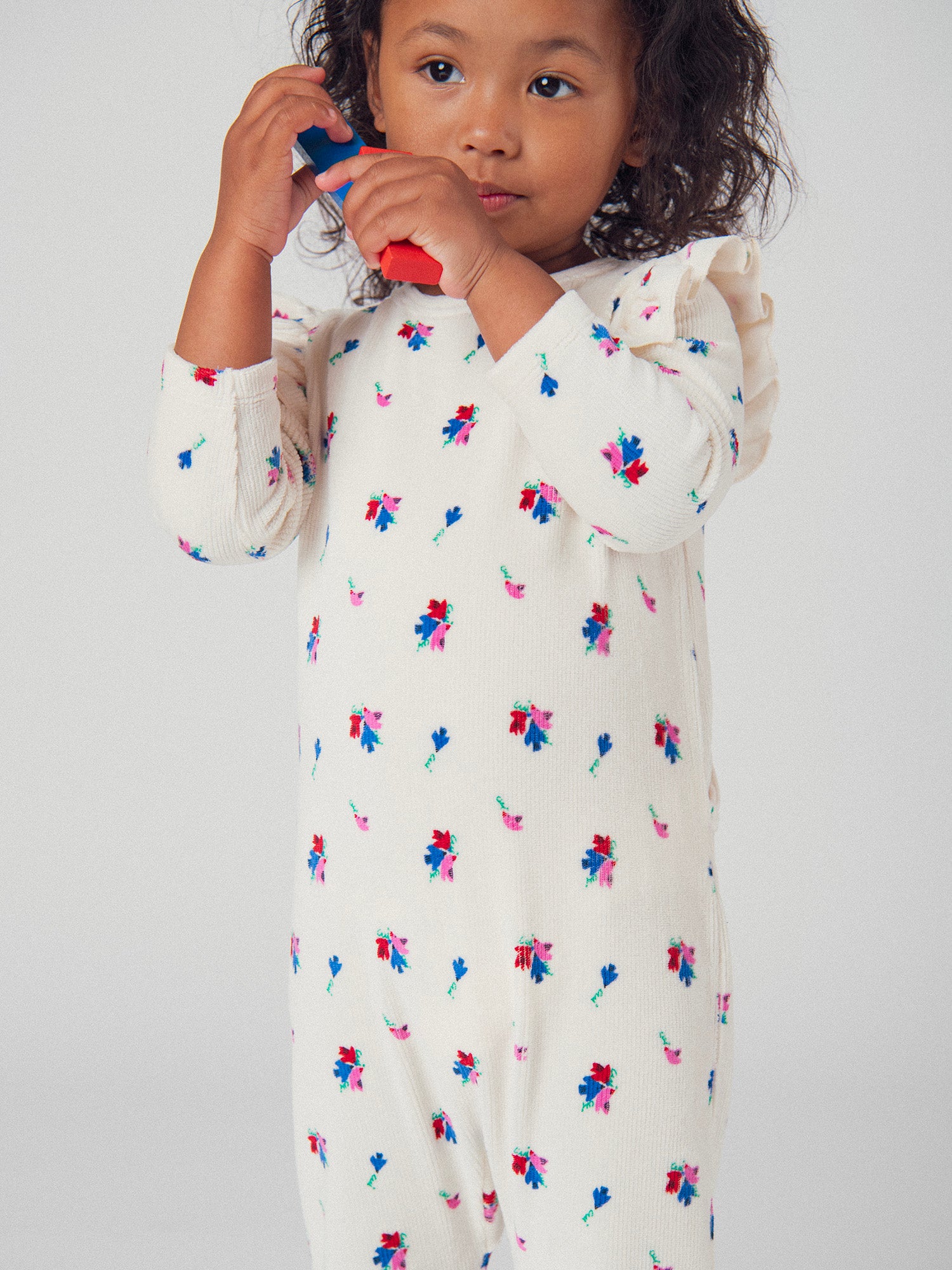 Macacão creme com folhos e padrões de pequenos pássaros e flores para menina